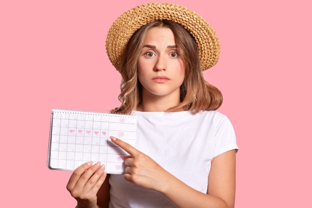 The current image has no alternative text. The file name is: woman-with-appealing-look-holds-periods-calendar-checking-menstruation-days-points-with-fore-finger-scaled.jpg